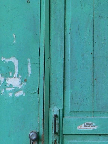 Old, narrow wooden door painted in vibrant blue color with slightly worn surface.
